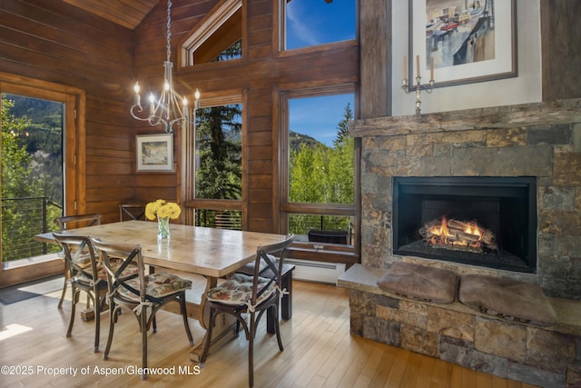 425 Crystal Park Dr, Redstone, CO 81623 - dining area with hardwood / wood-style floors, healthy amount of natural light, a chandelier, a stone fireplace, and wood walls