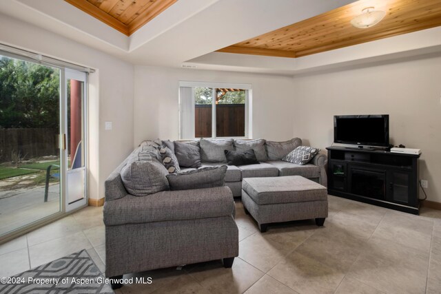 tiled living room featuring wooden ceiling and a tray ceiling