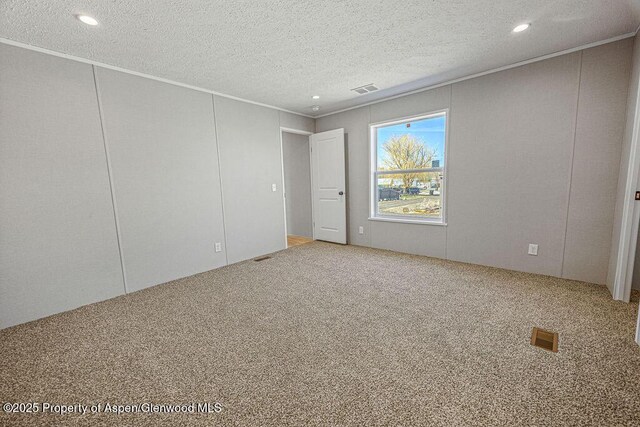 unfurnished room featuring ornamental molding, visible vents, carpet floors, and a textured ceiling
