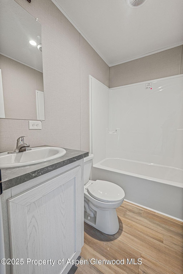 full bath featuring vanity, ornamental molding, toilet, visible vents, and wood finished floors