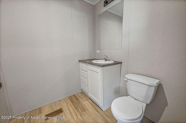 bathroom featuring toilet, wood finished floors, vanity, and visible vents