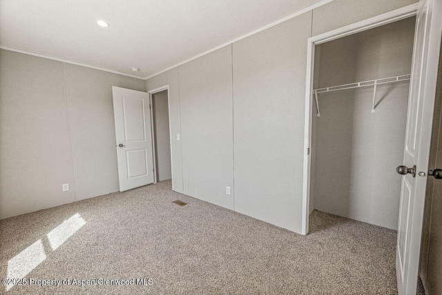 unfurnished bedroom featuring carpet flooring, visible vents, a closet, and crown molding
