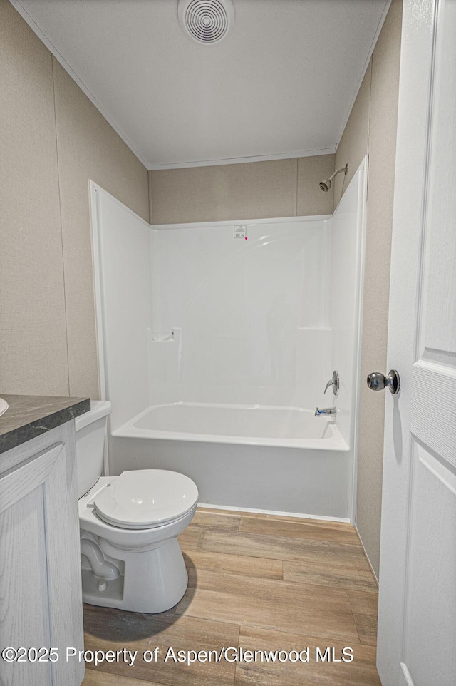 full bathroom with visible vents, toilet,  shower combination, vanity, and wood finished floors