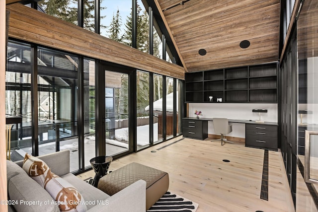 home office with wooden ceiling, high vaulted ceiling, built in desk, and light hardwood / wood-style floors