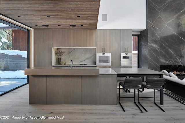 411 Pearl Ct, Aspen, CO 81611 - kitchen with wooden ceiling, modern cabinets, light countertops, an island with sink, and light wood-style floors