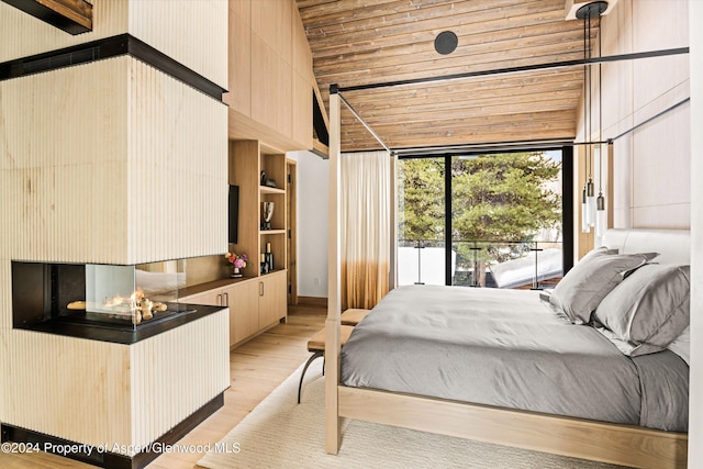 bedroom with access to exterior, light wood-type flooring, and vaulted ceiling