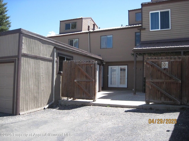 view of front facade with a gate, french doors, and metal roof