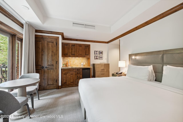 bedroom featuring a tray ceiling, sink, and light colored carpet