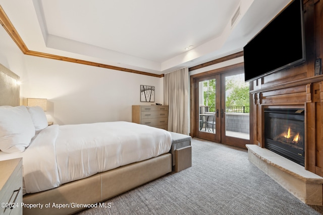 carpeted bedroom with french doors, access to outside, and a raised ceiling