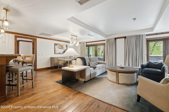 living room featuring a raised ceiling, an inviting chandelier, and plenty of natural light