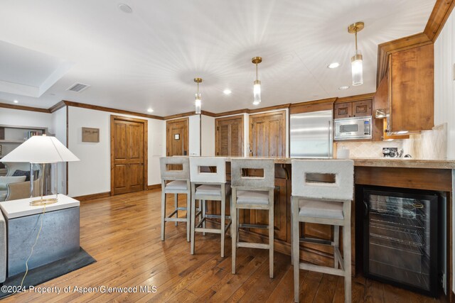 kitchen with beverage cooler, tasteful backsplash, light hardwood / wood-style flooring, built in appliances, and decorative light fixtures