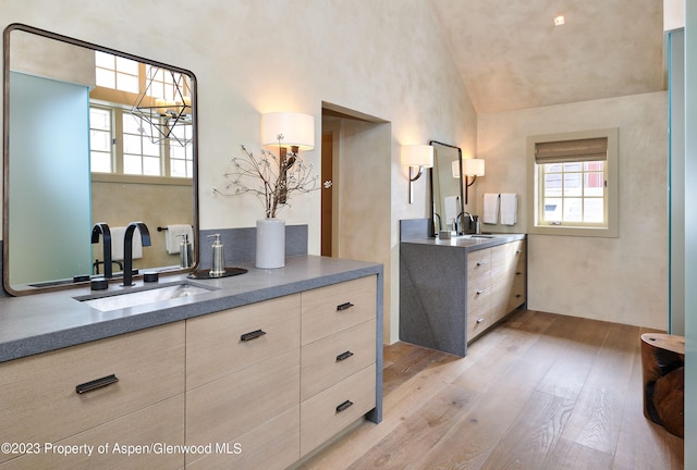 1271 Ute Ave, Aspen, CO 81611 - bathroom featuring wood finished floors, two vanities, high vaulted ceiling, and a chandelier