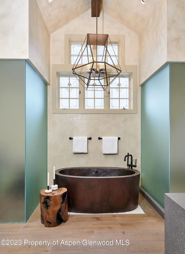 1271 Ute Ave, Aspen, CO 81611 - bathroom with wood finished floors, a freestanding tub, high vaulted ceiling, and a chandelier