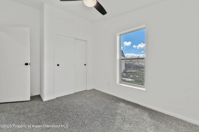 unfurnished bedroom with baseboards, carpet floors, ceiling fan, and a closet