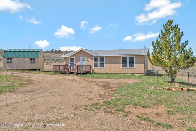 back of house with an outbuilding, crawl space, a wooden deck, dirt driveway, and a shed
