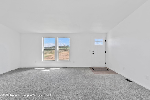 unfurnished living room with baseboards, visible vents, and carpet