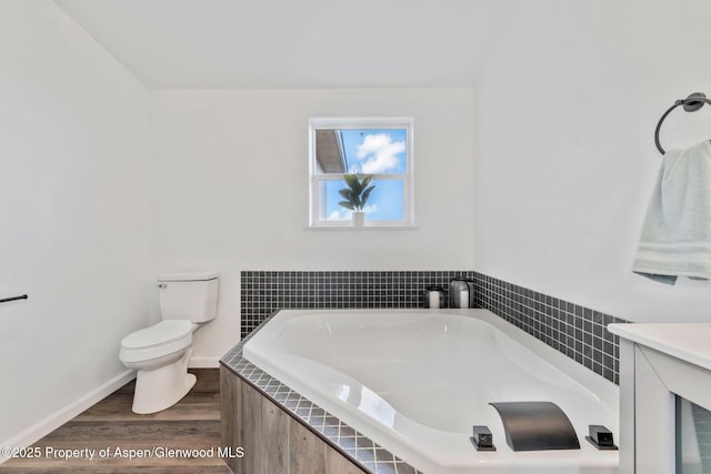bathroom with wood finished floors, a garden tub, toilet, and baseboards