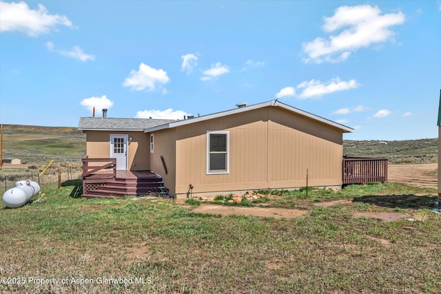 back of property featuring a wooden deck and a yard