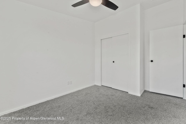 unfurnished bedroom featuring a closet, carpet flooring, baseboards, and ceiling fan