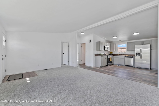 unfurnished living room with recessed lighting, light carpet, and a sink