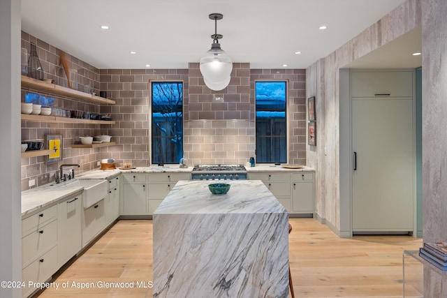 kitchen with range, light wood-type flooring, hanging light fixtures, and sink