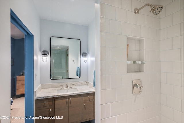 bathroom featuring tiled shower and vanity