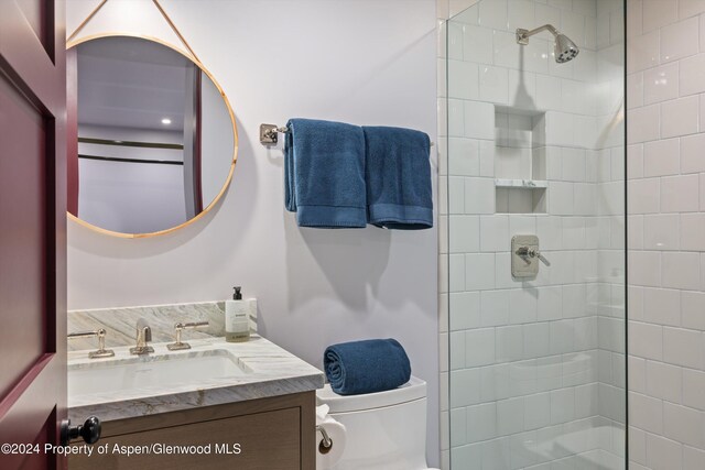 bathroom with a tile shower, vanity, and toilet