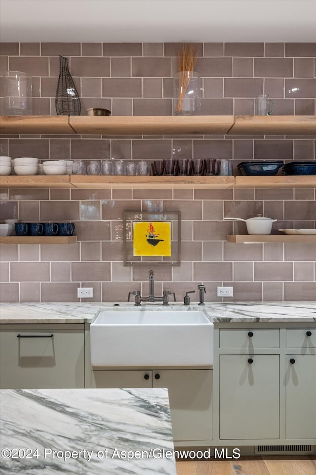 room details featuring backsplash, light stone counters, and sink