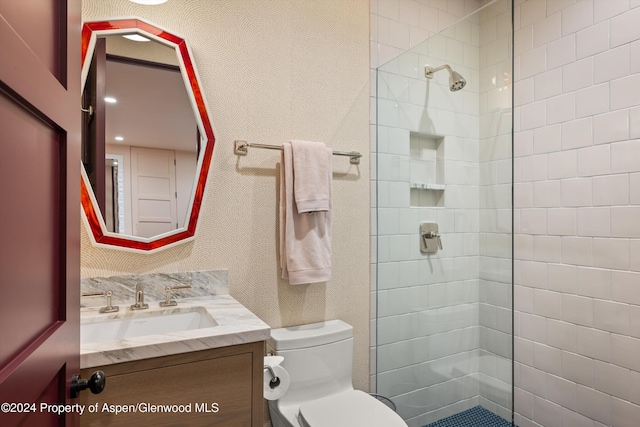 bathroom featuring tiled shower, vanity, and toilet