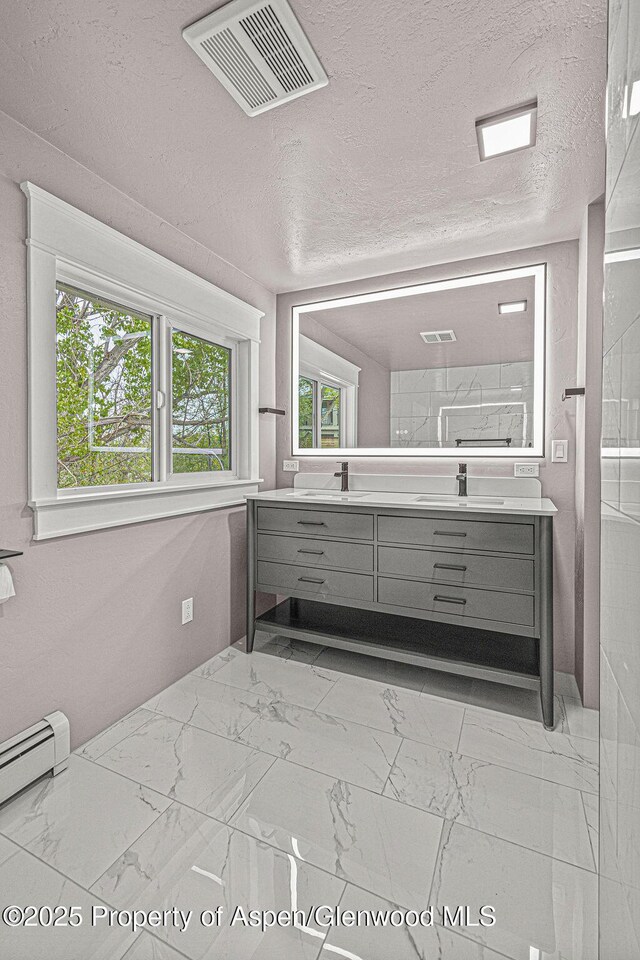885 Stout St, Craig, CO 81625 - bathroom featuring marble look tiles, double vanity, a textured ceiling, and a baseboard heating unit