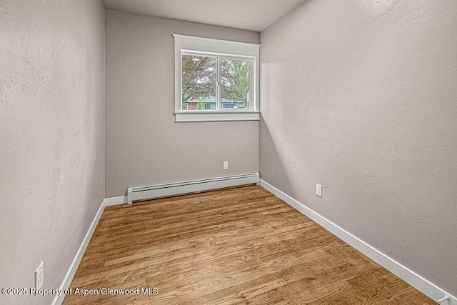 885 Stout St, Craig, CO 81625 - unfurnished room with baseboard heating, wood finished floors, baseboards, and a textured wall