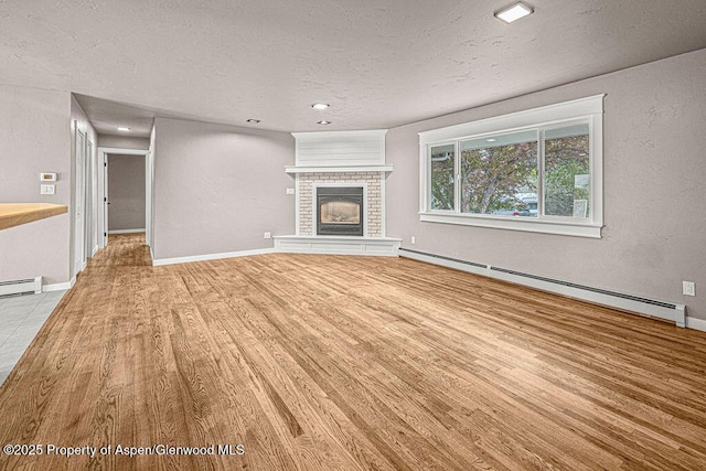 885 Stout St, Craig, CO 81625 - unfurnished living room featuring a baseboard heating unit, a textured ceiling, light wood-type flooring, a brick fireplace, and baseboards