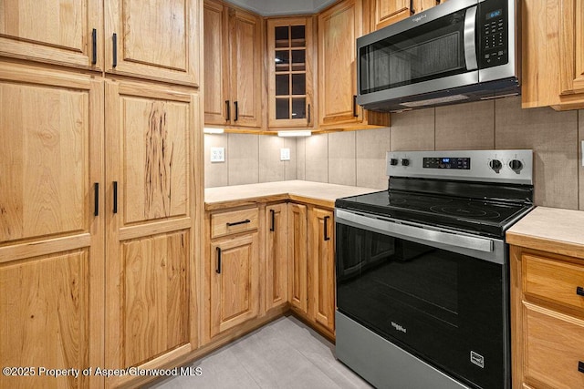 885 Stout St, Craig, CO 81625 - kitchen featuring appliances with stainless steel finishes, light countertops, decorative backsplash, and glass insert cabinets