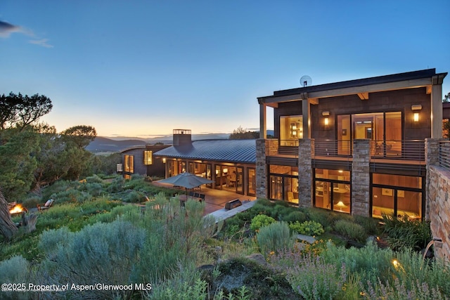 back house at dusk with a balcony