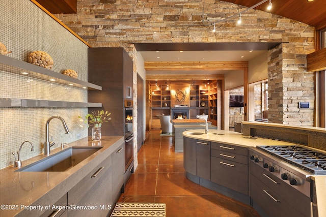 kitchen with lofted ceiling, sink, appliances with stainless steel finishes, dark tile patterned flooring, and decorative backsplash