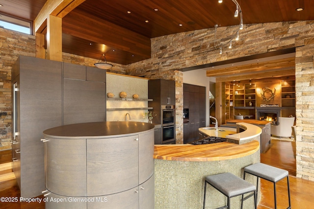 kitchen featuring sink, wood ceiling, double oven, black gas stovetop, and a high ceiling