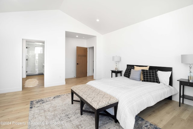 bedroom featuring hardwood / wood-style floors, high vaulted ceiling, and ensuite bath