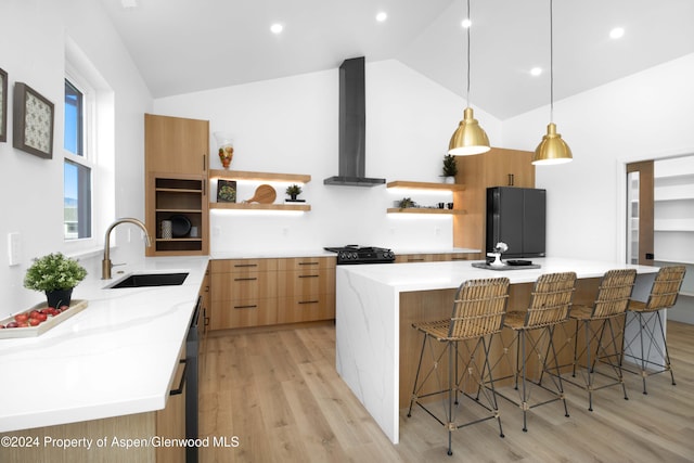 kitchen featuring a spacious island, hanging light fixtures, wall chimney exhaust hood, and sink