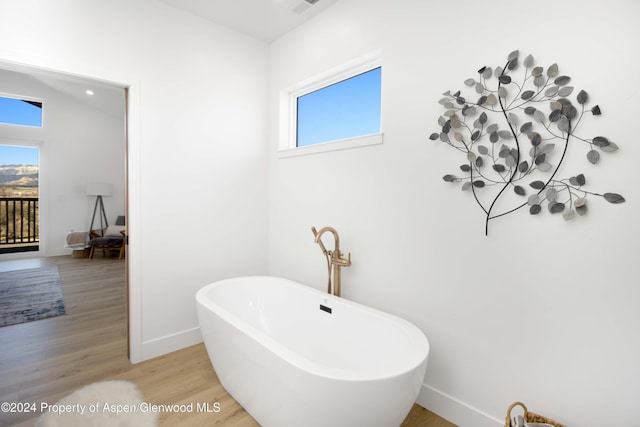 bathroom featuring a bathing tub, vaulted ceiling, and hardwood / wood-style flooring