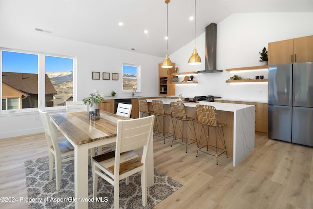 dining area featuring light wood-type flooring, sink, and vaulted ceiling