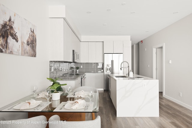 kitchen featuring sink, stainless steel appliances, a kitchen island with sink, decorative backsplash, and white cabinets