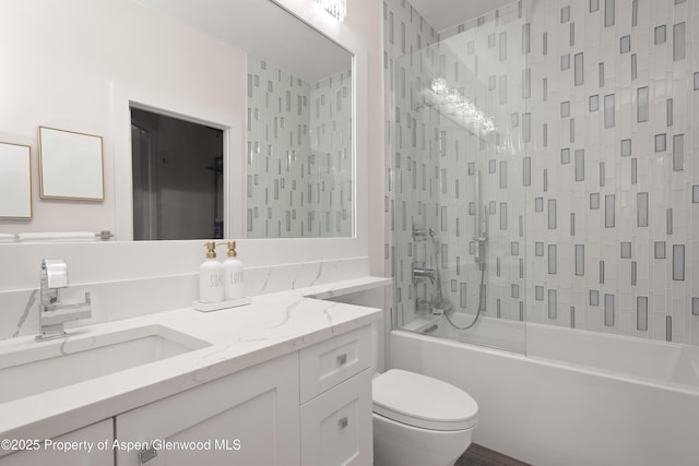 full bathroom with tiled shower / bath, vanity, and toilet