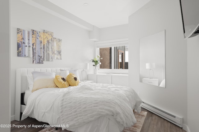 bedroom with a baseboard heating unit and dark hardwood / wood-style floors