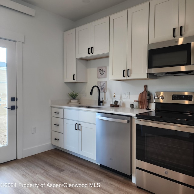 kitchen featuring white cabinetry, sink, stainless steel appliances, and light hardwood / wood-style flooring