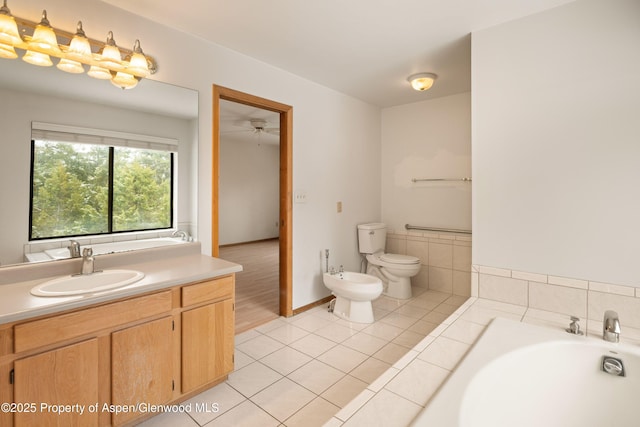 bathroom featuring tile patterned flooring, vanity, toilet, a bidet, and a bath