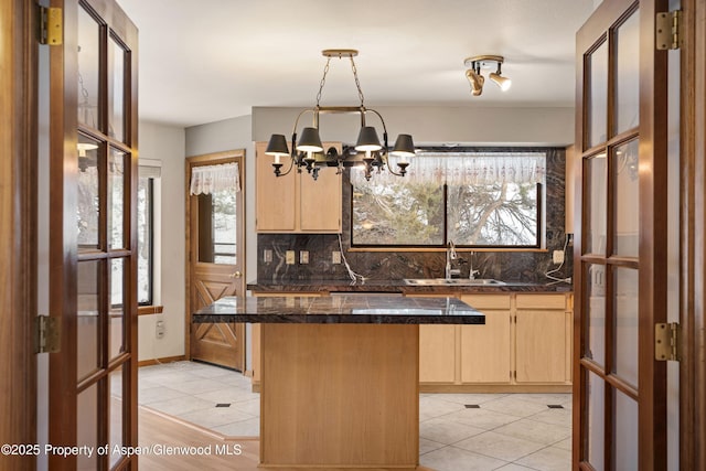 kitchen featuring sink, light tile patterned floors, tasteful backsplash, a notable chandelier, and light brown cabinetry