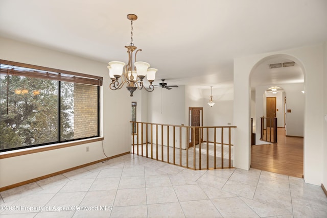 tiled spare room with ceiling fan with notable chandelier