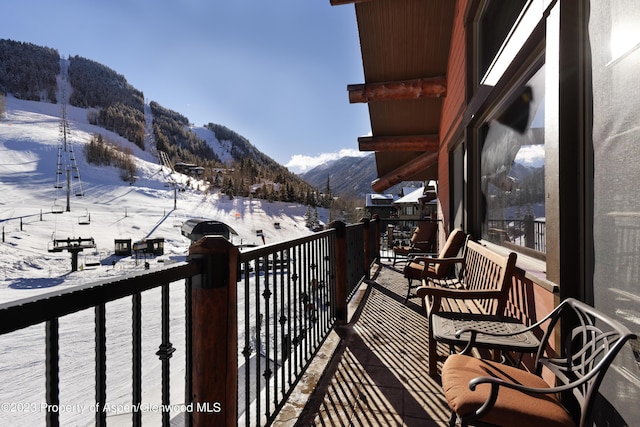 snow covered back of property featuring a mountain view