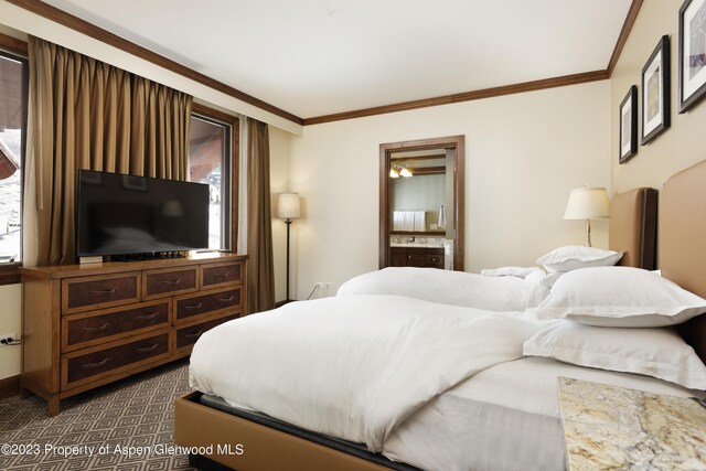 bedroom with dark carpet, crown molding, and connected bathroom