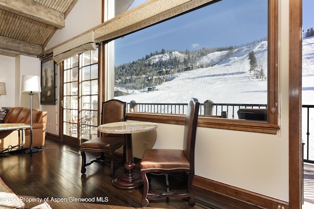 dining area with vaulted ceiling with beams, a mountain view, wood ceiling, and dark hardwood / wood-style floors